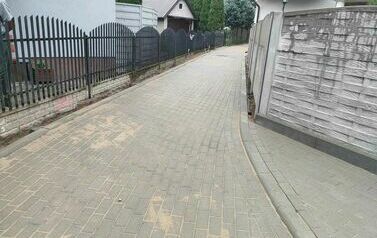 Na zdjęciu ogordzenia, budynki oraz droga z kostki betonowej