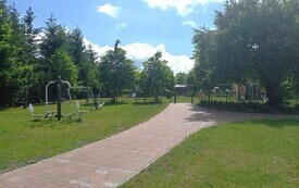 Siłownia plenerowa i w oddali plac zabaw