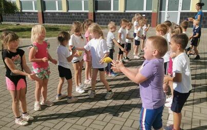 Grupa dzieci ierze udział w sportowej zabawie podrzucając do siebie woreczki